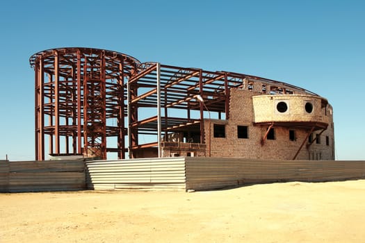 Partially coated iron frame with brick building under construction.