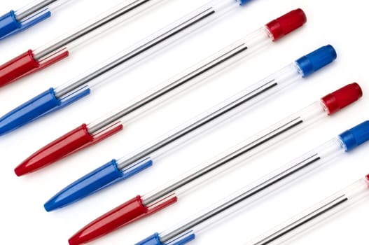 A selection of red and blue pens arranged diagonally over white