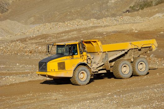 A yellow dump truck is driving in a mine