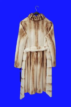 Fur Women's coat on a hanger, isolated on a blue background.