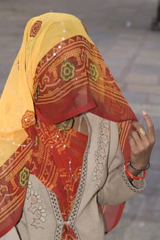 Indian woman with brightly coloured orange veil over her head
