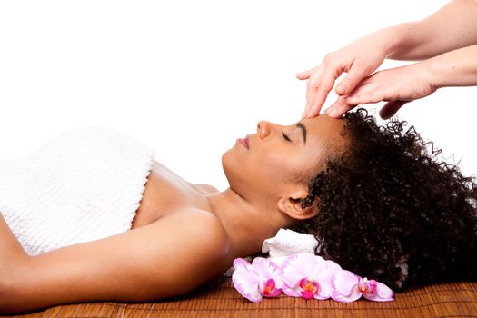 Beautiful happy peaceful sleeping woman at day spa, laying on bamboo massage table with head on pillow wearing a towel getting a facial massage, isolated.