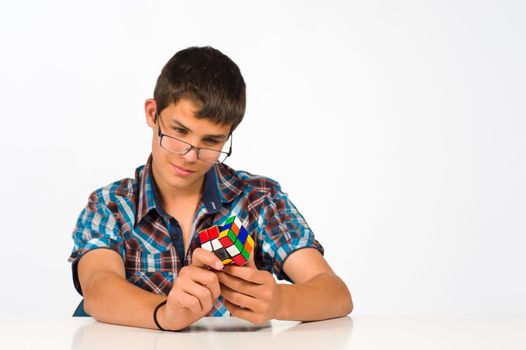 Teenager with glasses playing with a cube