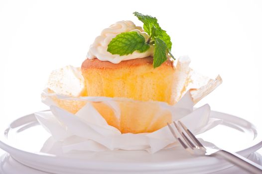 Cupcake with vanilla cream and mint leaf on a white background