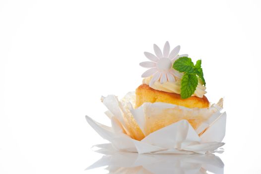 Cupcake with vanilla cream mint leaf and sugar flower on a white background