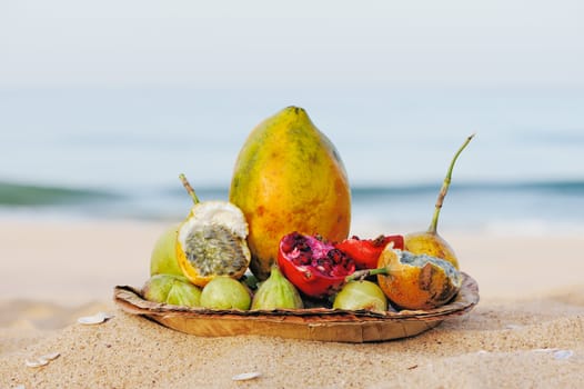 Exotic tropical fruit on the leaves plate, on the sandy beach