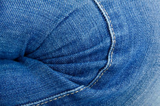 Women's knee in jeans with folds closeup