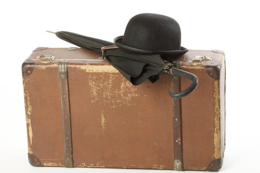 Old suitcase, bowler hat and umbrella over white