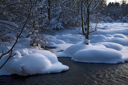 Winter landscape with a river and pine trees, snow falling, horizontal
