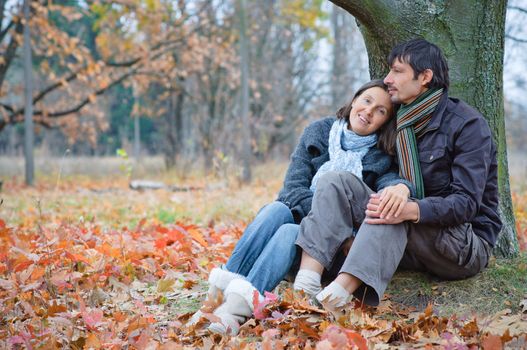 Romantic mature couple sitting in the autumn park.