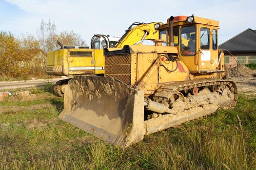 yellow bulldozer standing on the grass idly