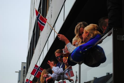 Happy norwegians watching the national day parade from a pub.