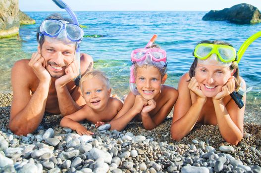 Happy family on beach with snorkles ready to have a good time swimming