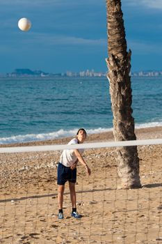 Teenager serving at a beach volley match