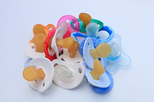 Stack of baby soothers of various colours