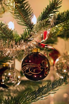 Dark red decorated ball in christmas tree with candle lights