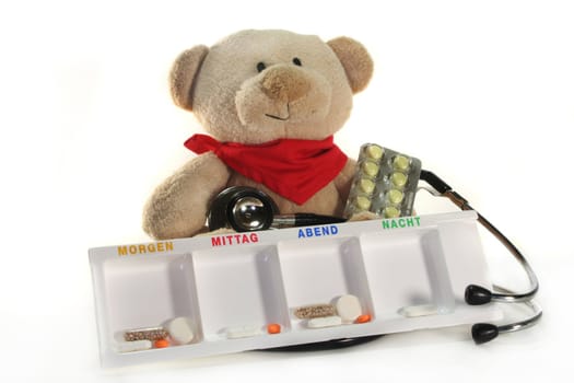 Teddy with a stethoscope and medication before a white background