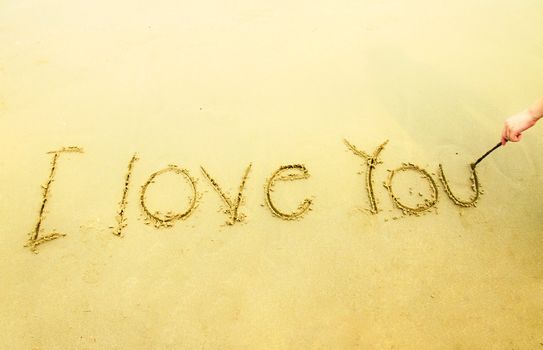 Hand writing I love you on sand at the beach