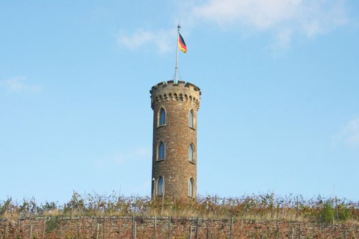Turm im Weinberg mit Deutscher Flagge,und blauem Himmel im Hintergrund	
Tower in the vineyard with the German flag and a blue sky in the background