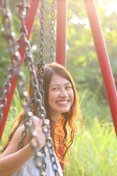A beautiful and cheerful asian woman playing swing