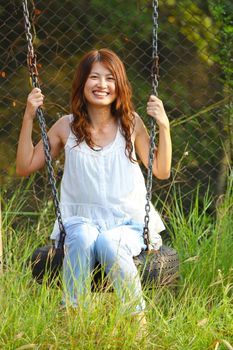 Asian girl playing swing in a park