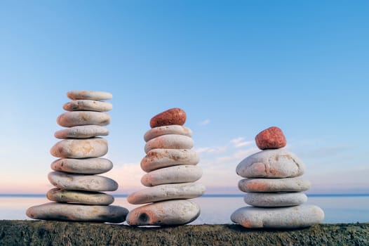 Balancing of three piles of pebbles near the sea