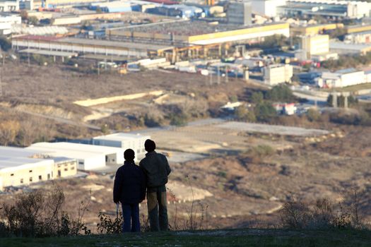 Silhouettes of two boys overlooking industrial zone