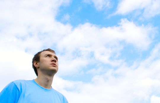 The young man looks at the blue sky

