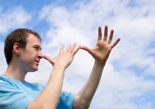 The young man plays about and wriggles against the blue sky