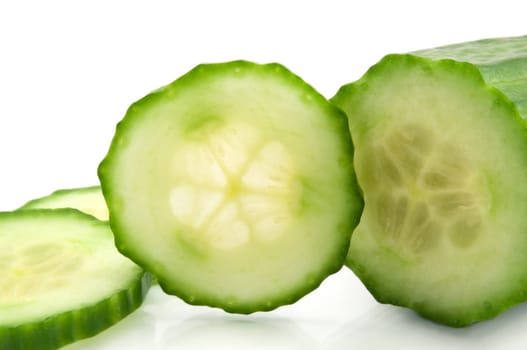 Close up of a partially sliced fresh organic cucumber arranged over white
