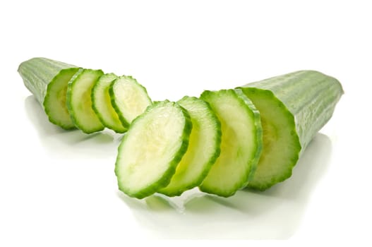 Two partially sliced fresh cucumber arranged over white
