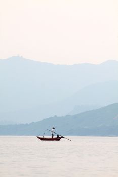 Fisherman over the ocean and between the mountain ridges