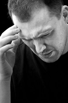 A man with an intense headache or migraine in black and white. He might be experiencing stress during a time of economic crisis or other hardship.