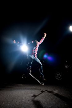 A skateboarder performs tricks under dramatic rim lighting with lens flare. 