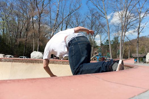 Action shot of a young skateboarder skating sideways against the wall of the bowl at a skate park.