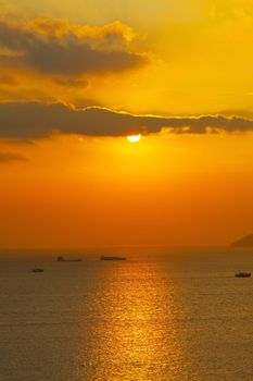 Sunset over the ocean with moving ships