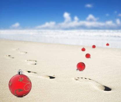 Christmas baubles on a beach with footprints