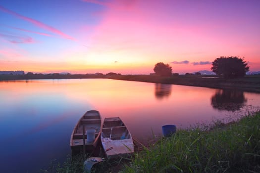 Sunset along the pond with isolated boats 
