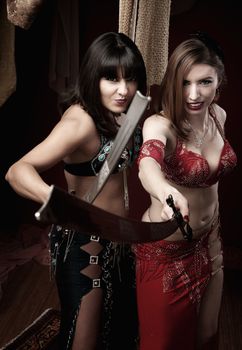 Two beautiful belly dancers hold traditional swords 