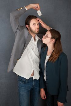 Distracted man combs hair while nerdy woman tries to kiss him