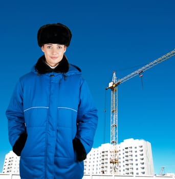 Young architect-woman wearing protective winter cloth standing on the building background