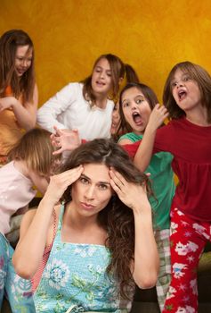 Babysitter holds head with wild little girls at a sleepover