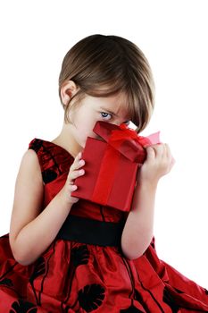 A young girl peeking into a gift she has received isolated against a white background with clipping path included.