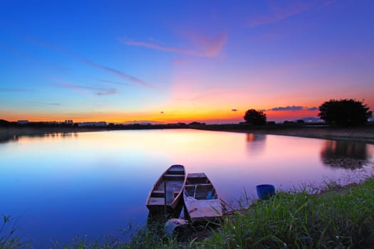 Sunset along the pond with two boats and two magical color on sky