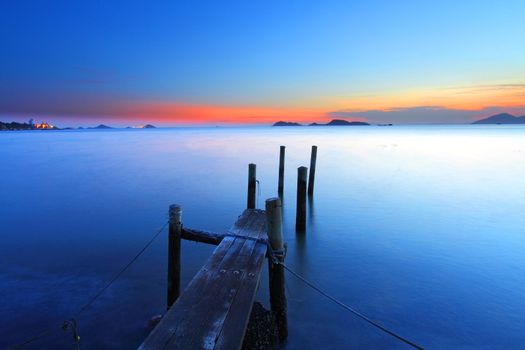 Sunset at dusk along a wooden pier, high saturation and long exposure image.