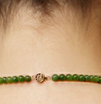 Green gemstone necklace, on female person, isolated rear view