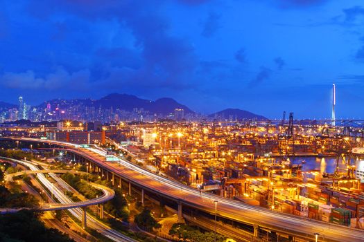 Busy traffic in Hong Kong at night with container terminal background