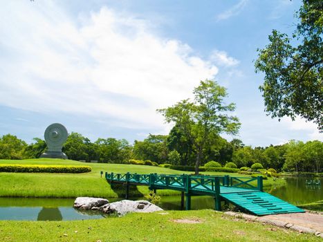 Green wooden bridge with Dharmacakra in Buddhamonthon, Nakhon Pathom, Thailand