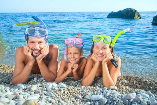 Happy family on beach with snorkles ready to have a good time swimming