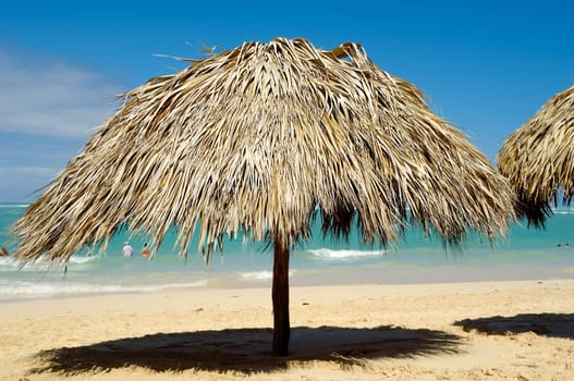 Parasol made out of palm leafs on beach.